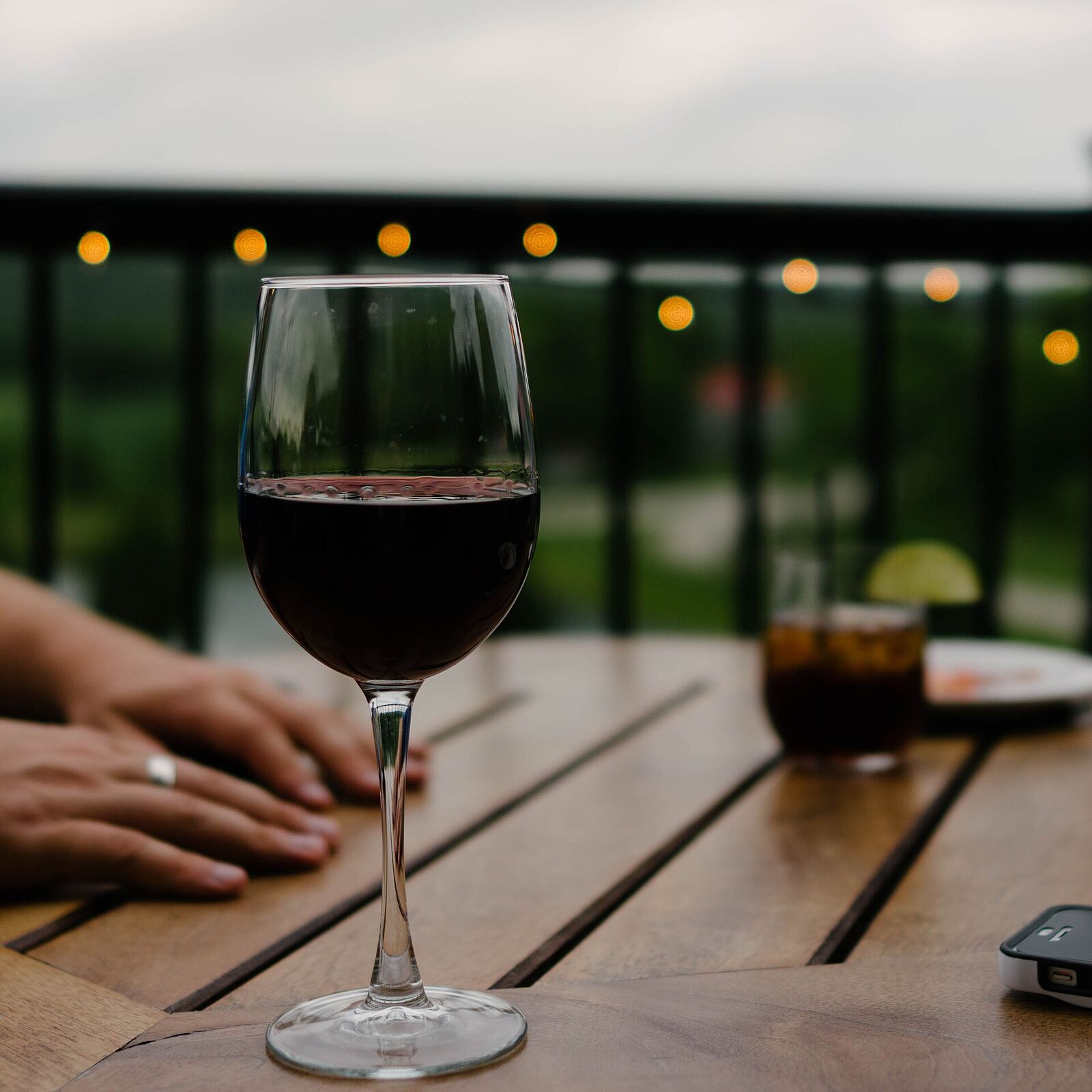 Glas Rotwein auf einem Holztisch auf der Terrasse am Abend
